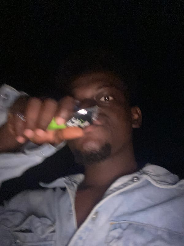 Person vaping at night near illuminated shop area