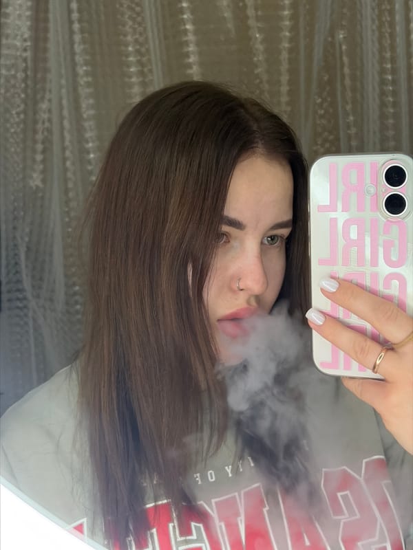 Person with nose ring photographed smoking, holding pink phone case