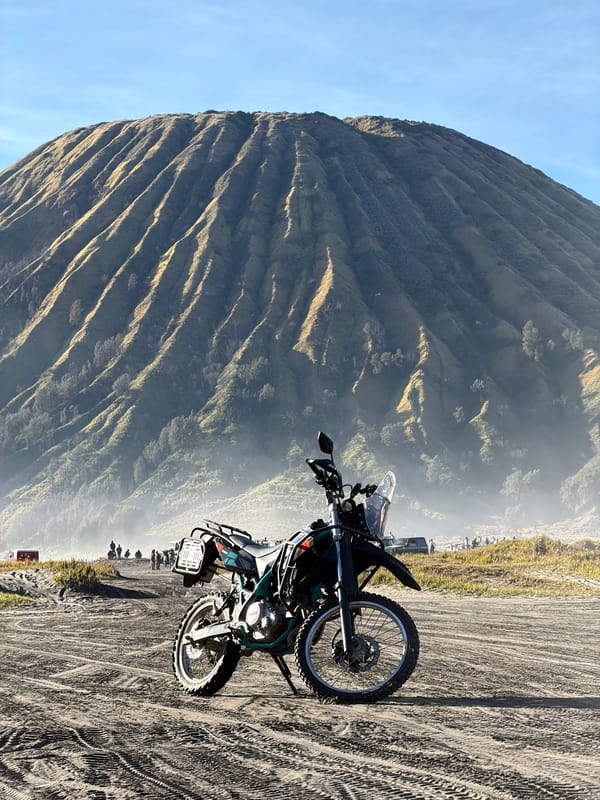Dirt bike parked on sandy plains below Mount Bromo