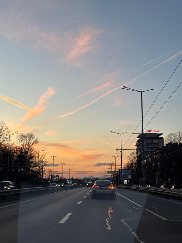 Dusk streetscape documented in Sofia with contrails overhead