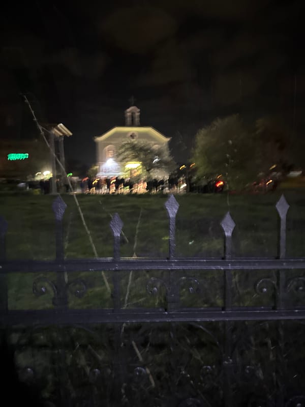 Person photographs domed building through fence in Sofia at night