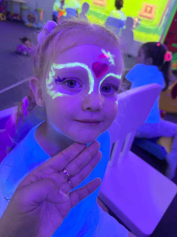 Glow-lit indoor kids' party with face paint, VR, and games