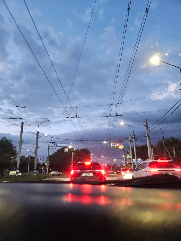 Dense trolley wire network overhead at dusk in an urban street