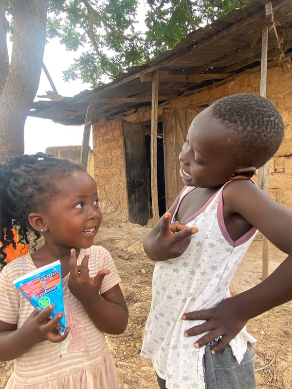 Two girls share juice boxes in Kuru Dungus, Nigeria