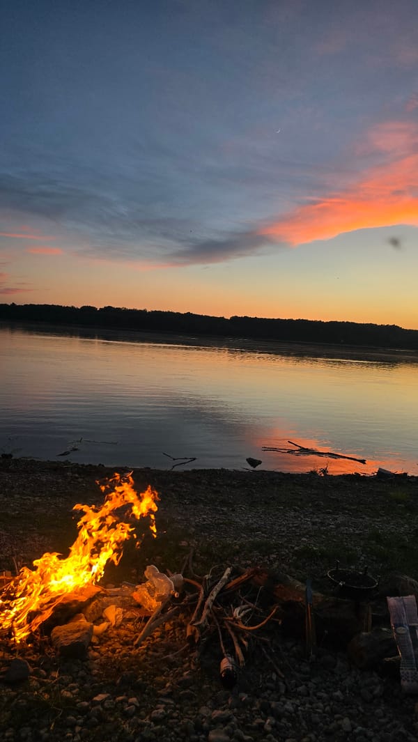 Campfire and fishing on a rocky shore at dusk