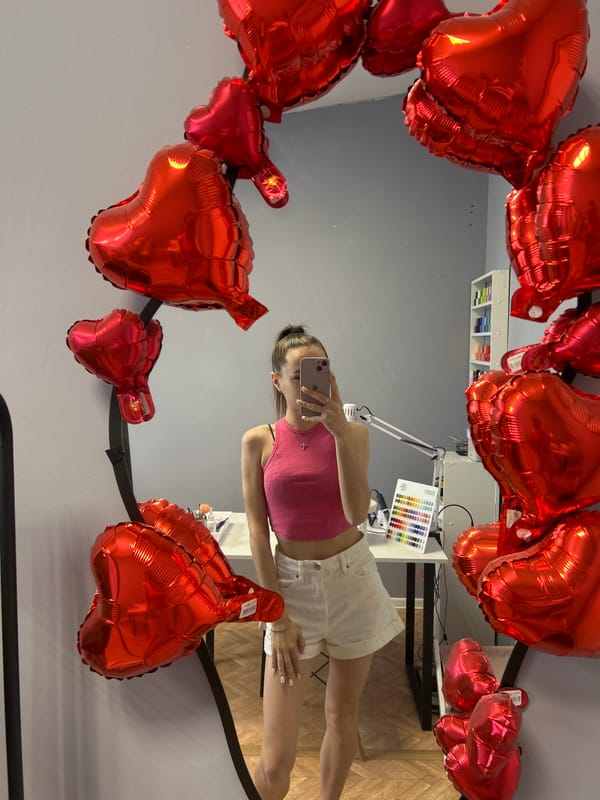 Young woman photographs herself with heart balloons, furniture