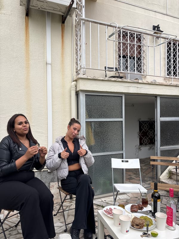 Two women gather on Lisbon balcony under overcast skies