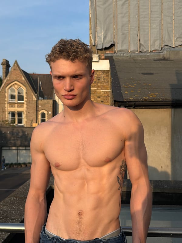 Tattooed man poses shirtless on London rooftop