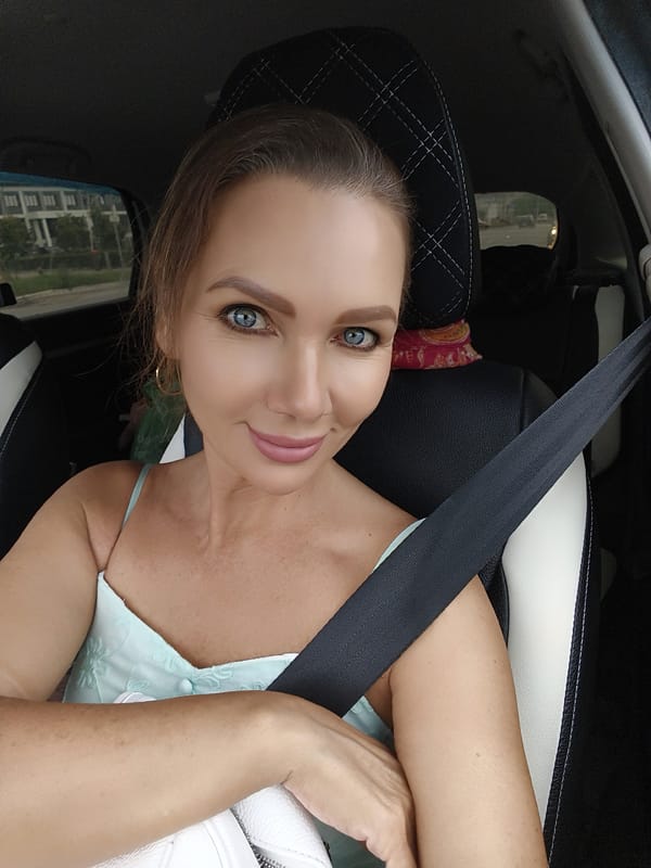Two people inside a car, both in light blue