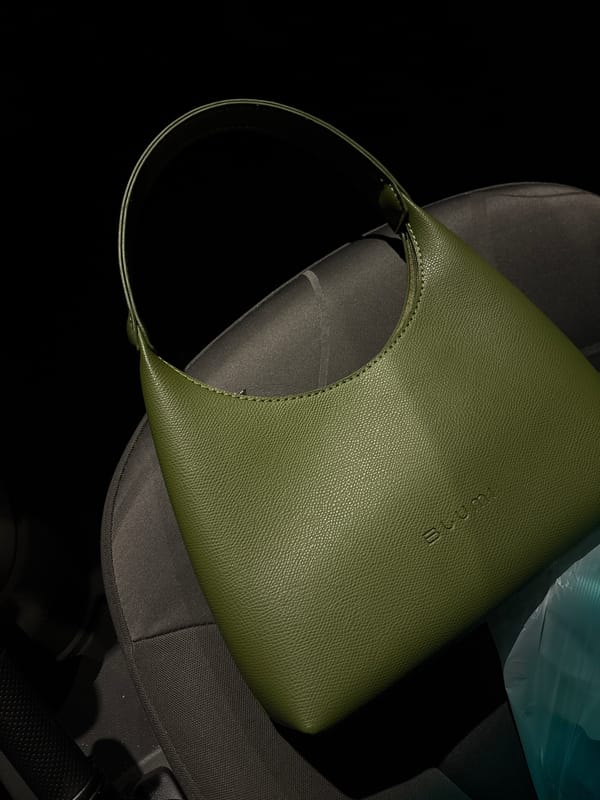 Olive green handbag photographed on car seat in Ust-Ilimsk
