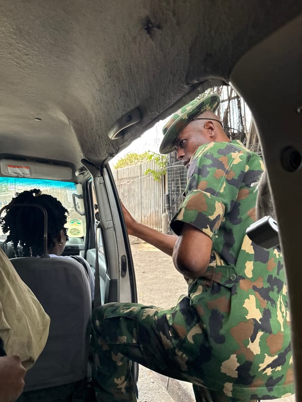 Military personnel interact with civilians near vehicle in Lagos