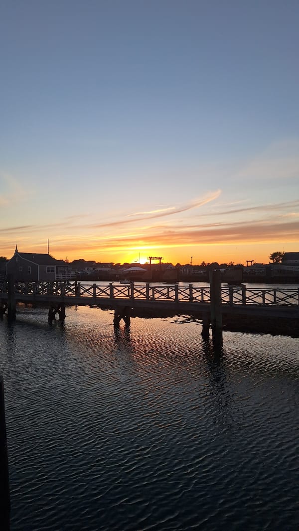 Warm sunset over Nantucket harbor from a wooden boardwalk