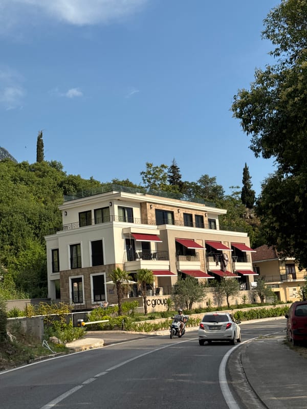 White hillside building with red awnings in Dobrota, Montenegro
