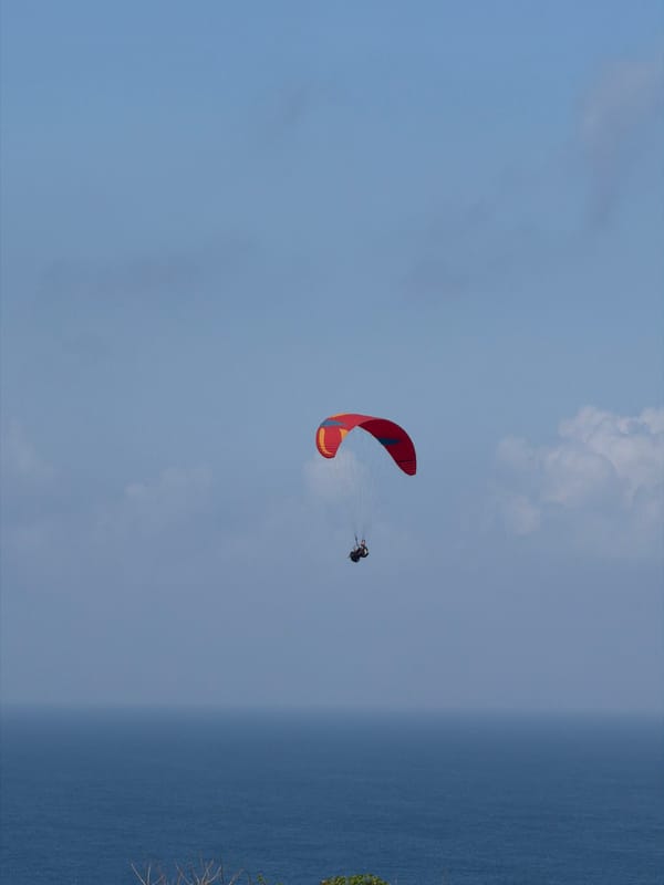 Paragliders over the Bali coast, construction work below