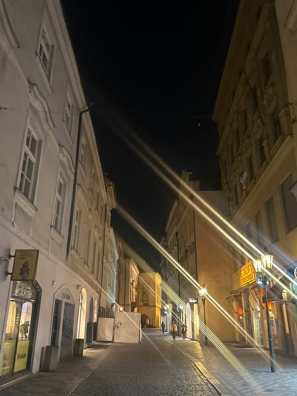 Nighttime Prague street scene with chimney cake signage documented