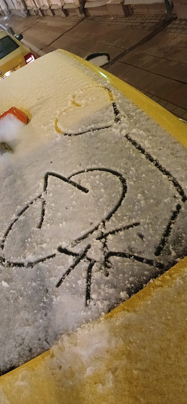 Snow-covered yellow car displays graffiti lettering in Moscow