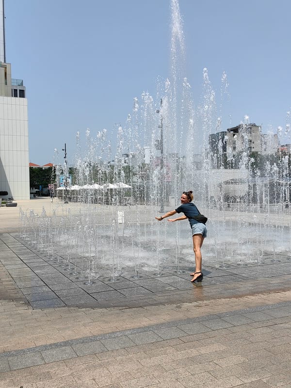 Woman plays at fountain in Hanoi public square