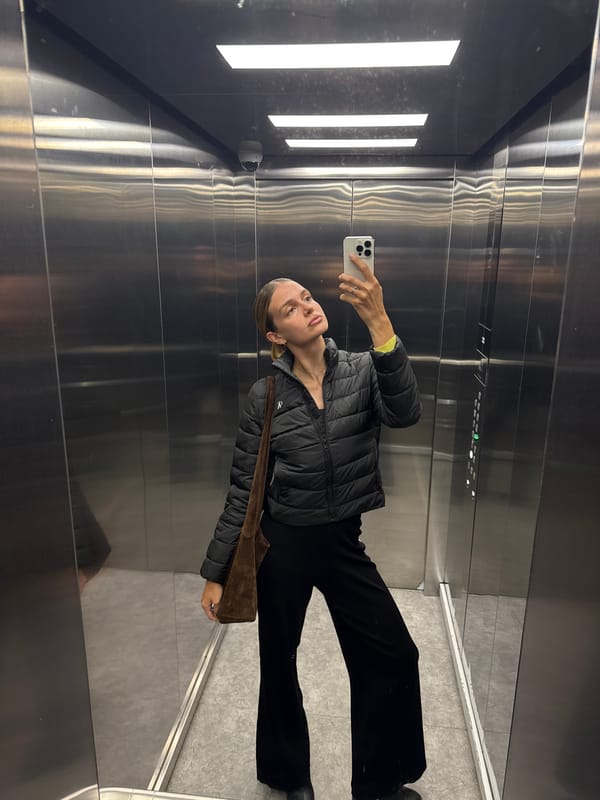 Woman takes selfie in elevator wearing black outfit