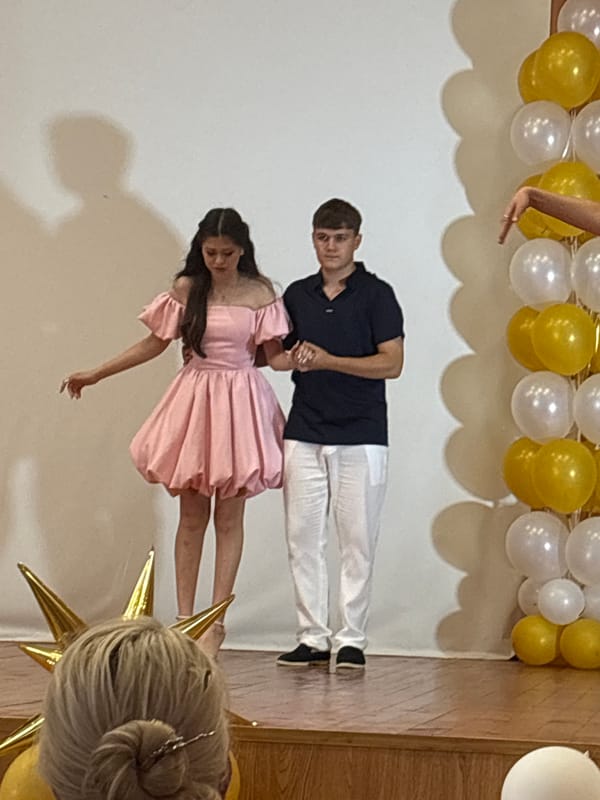 Graduation and awards ceremony with certificates, flowers, and a stage performance