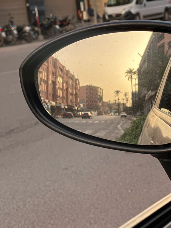 Dusty car mirror reflects Marrakesh street scene