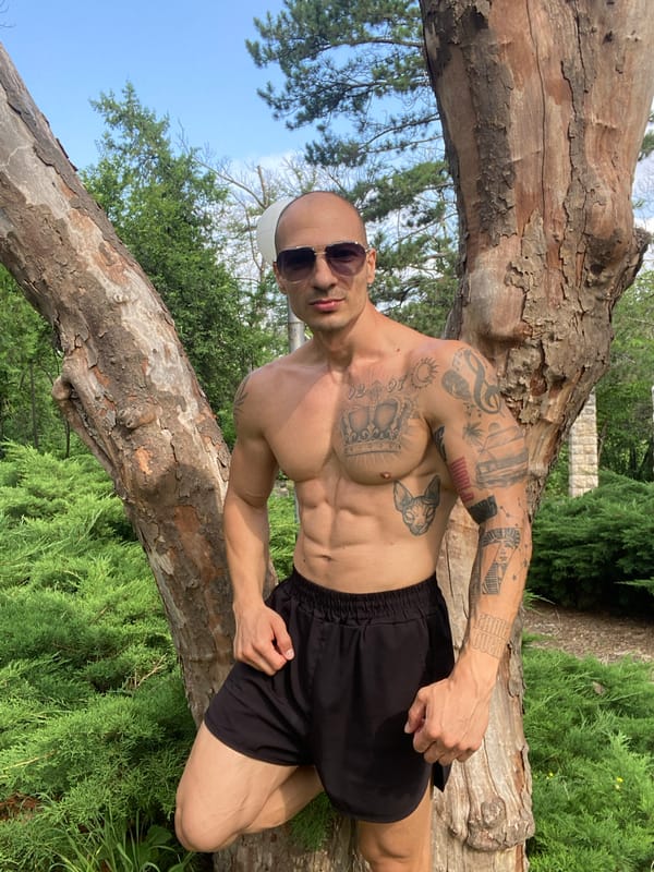 Tattooed figure poses shirtless in Pleven park, July morning