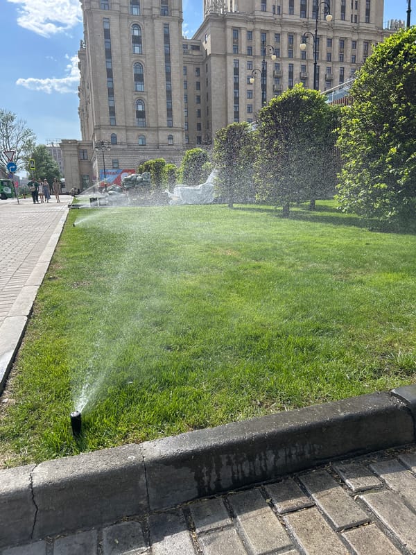 Urban lawn sprinklers create rainbow effects in afternoon sunlight