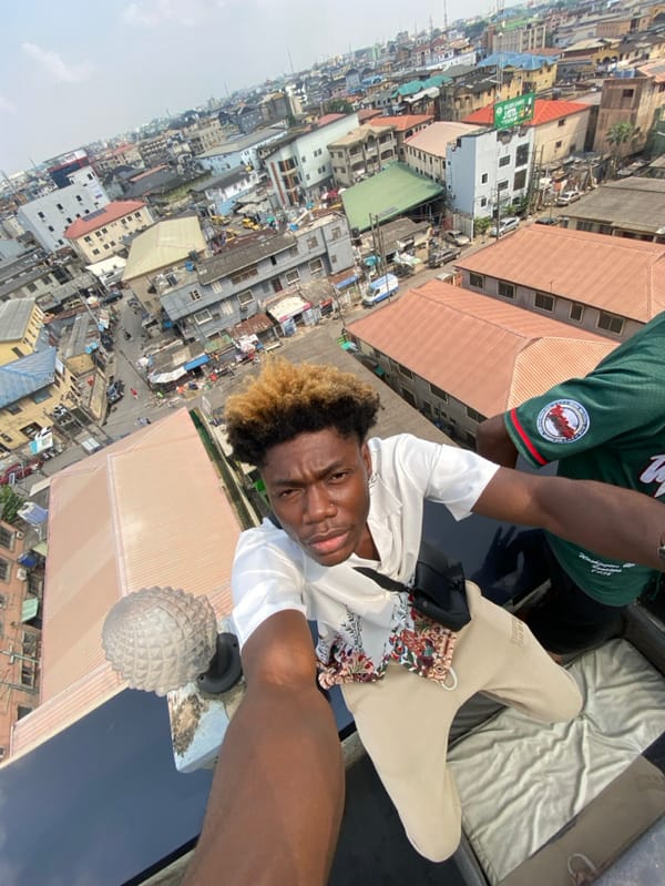 Young men take rooftop selfies overlooking Ikeja cityscape