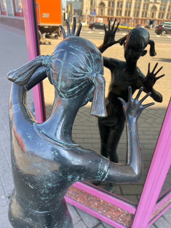 Bronze statue reflected in decorative mirror on Minsk street