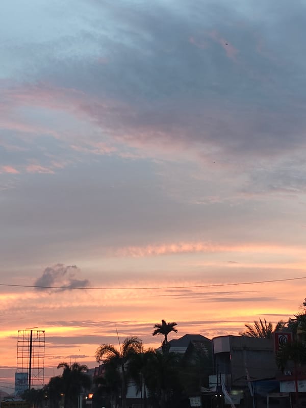 Lhokseumawe street traffic under a vivid sunset sky