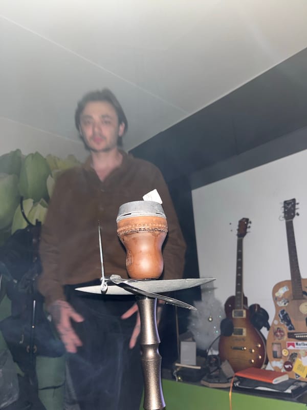 Man with hookah photographed in guitar-decorated indoor space
