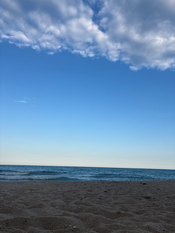 Quiet beach day with a yacht offshore and a few people out