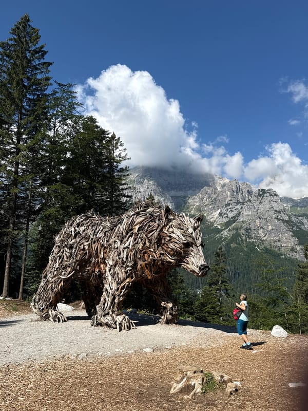 Wooden bear sculpture and log water trough in Molveno