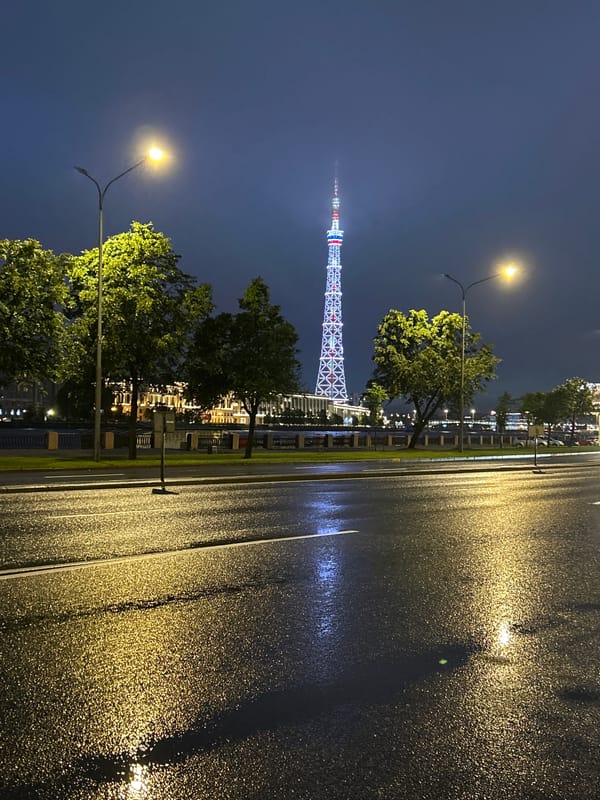 Wet streets and a glowing tower on a rainy St. Petersburg night