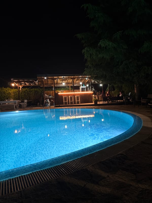 Blue-lit pool beside an outdoor bar in Ravda at night