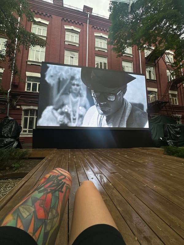 Outdoor screen and tattooed leg on a Moscow wooden deck