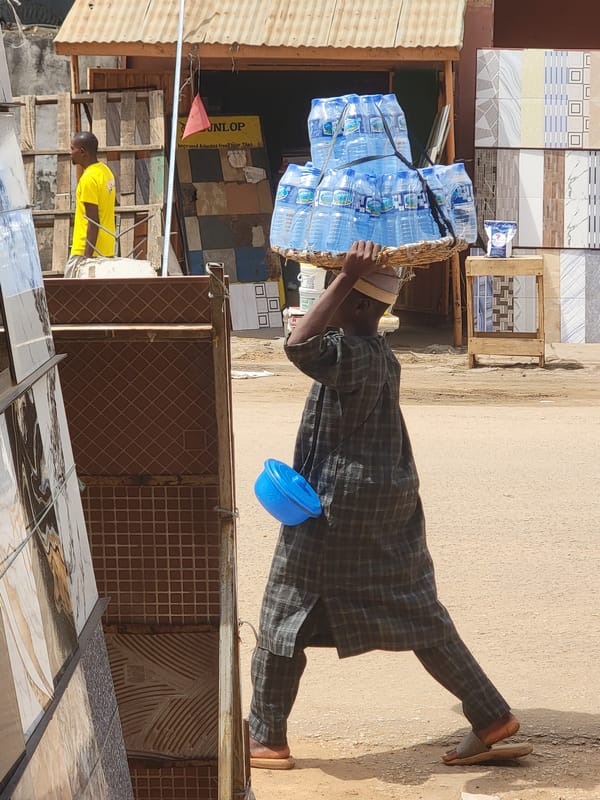Men carry water bottles and clothing goods in Maiburiji