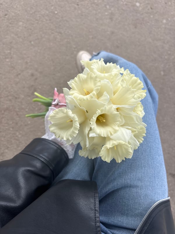 Person with daffodil bouquet sits on Krasnodar sidewalk