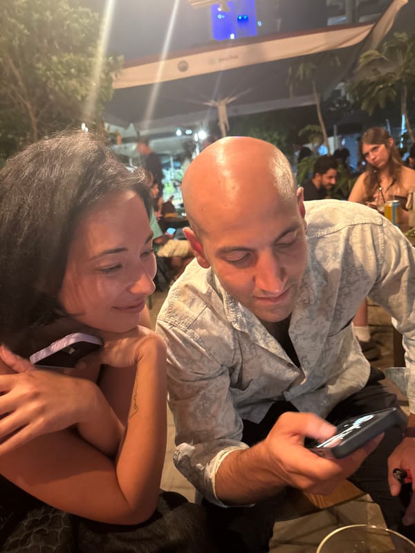 Outdoor café table, Tel Aviv — phone check mid-conversation
