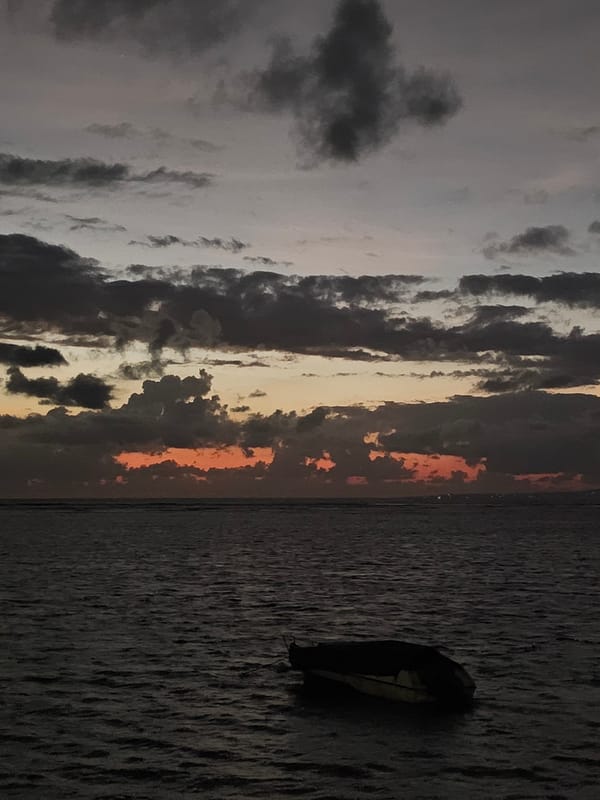 Post-sunset coastline near Denpasar, moody skies and anchored boats
