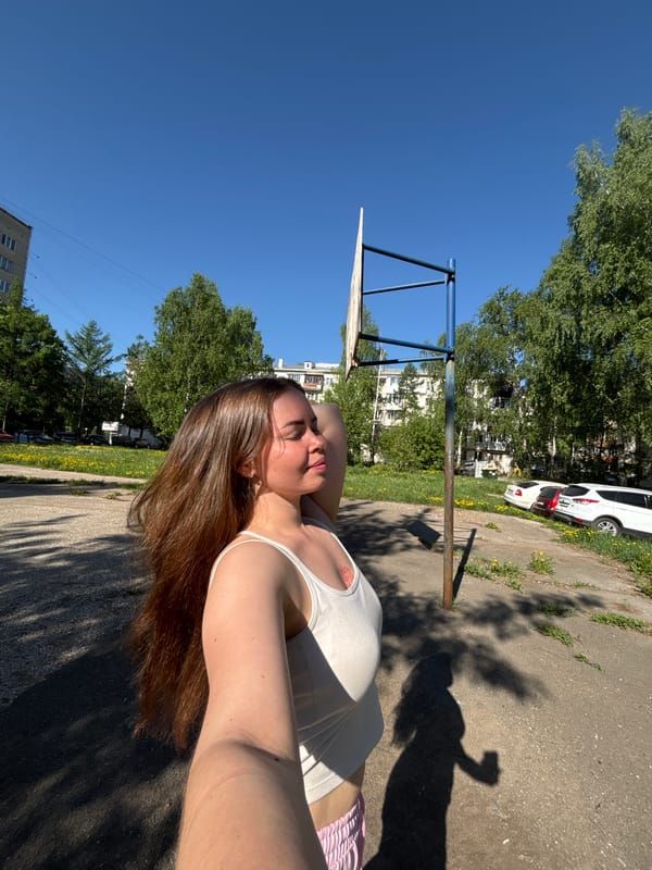 Woman rests near basketball court as dog walks nearby