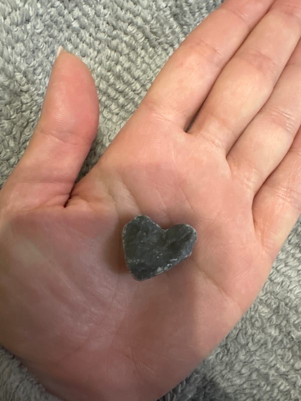 Private bedroom moment with heart-shaped stone and gift documented