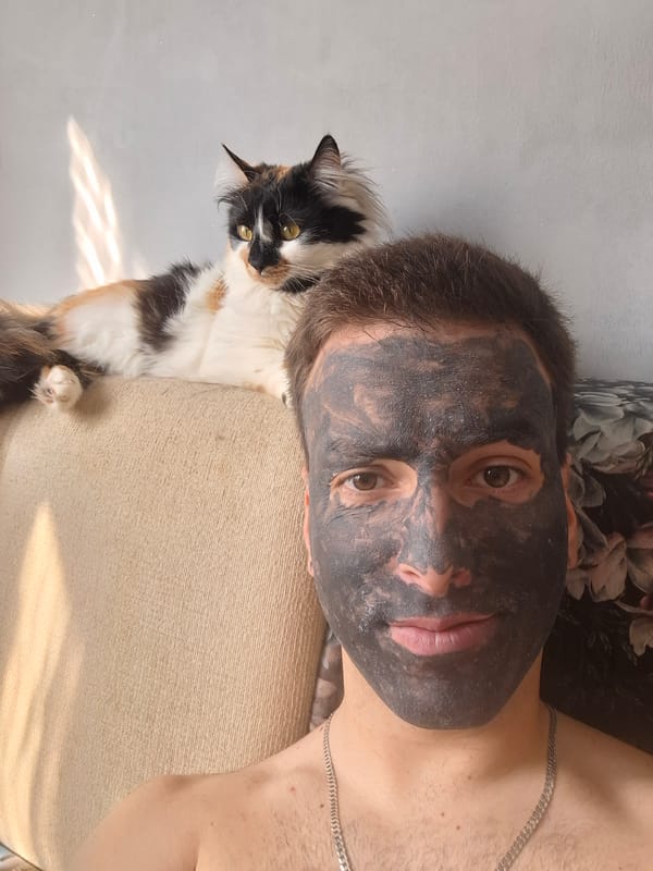 Man in face mask rests with calico cat indoors