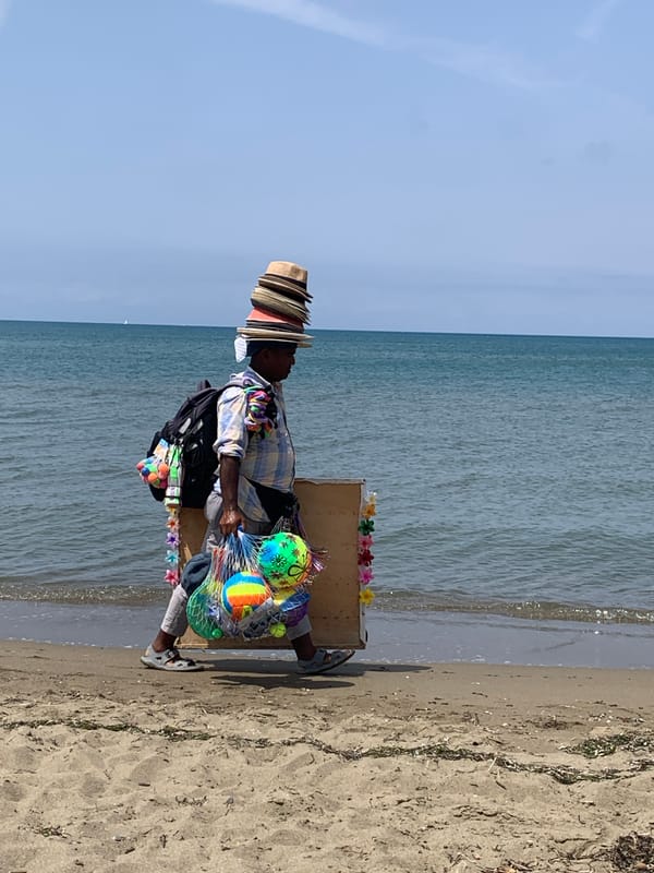 Hat vendor strolls Orbetello beach loaded up for business