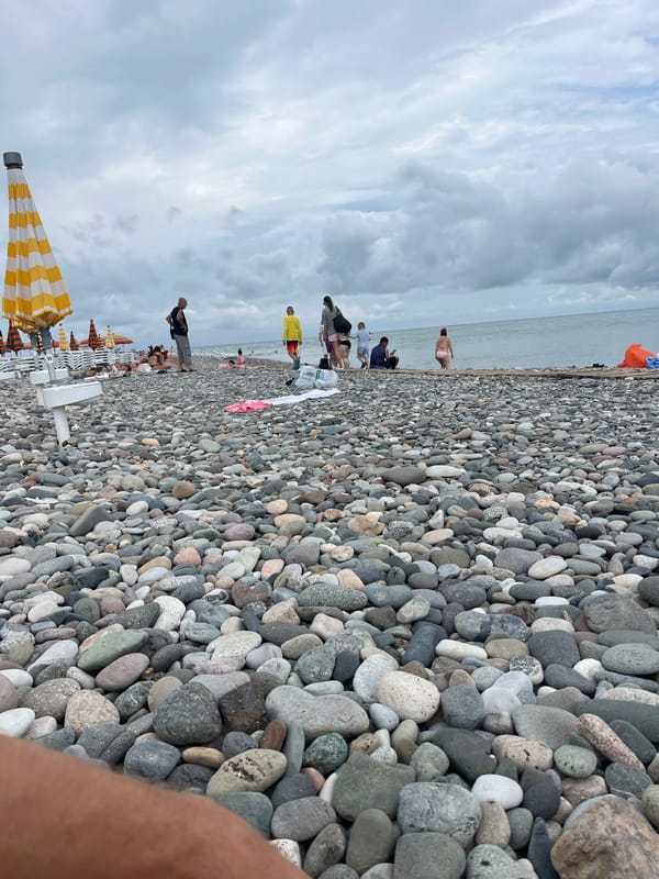 Busy morning on Batumi's pebble beach under cloudy skies
