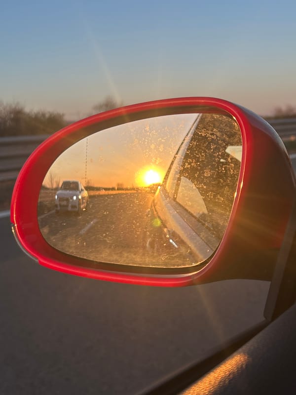 Driver captures sun-drenched road reflection in car mirror, Bulgaria