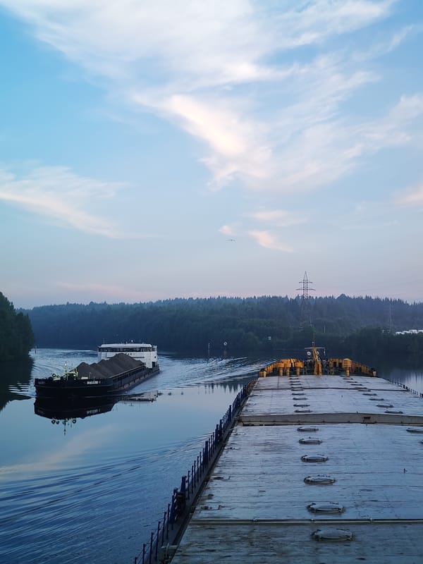 Barges hauling sand down a forested Russian river