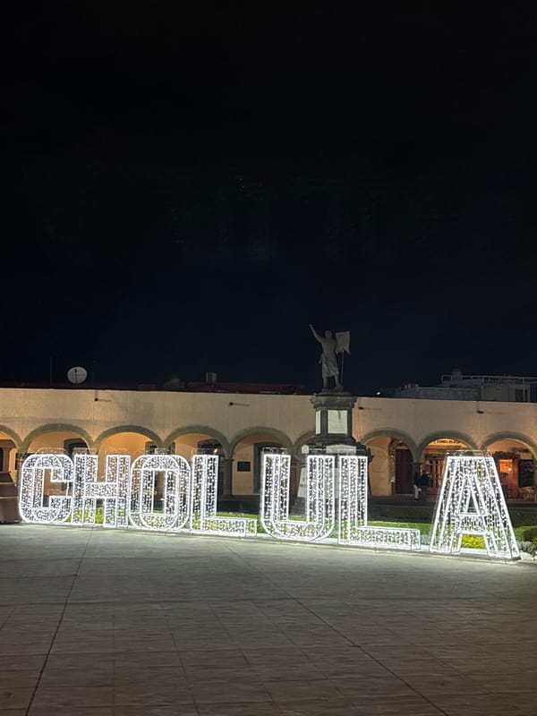 Illuminated Cholula sign glows beside municipal building at night