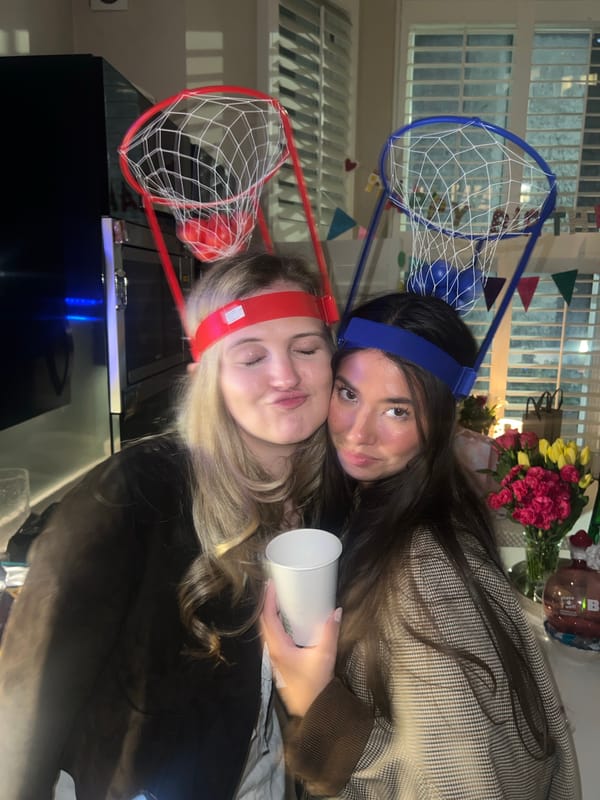 Two women celebrate with basketball hoop headbands in London