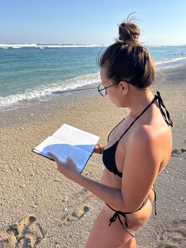 Woman reads book aloud on Indonesian beach morning