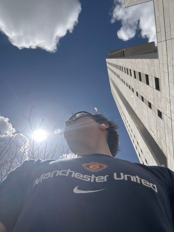 Person in Manchester United shirt observes modern building in Ramat Gan